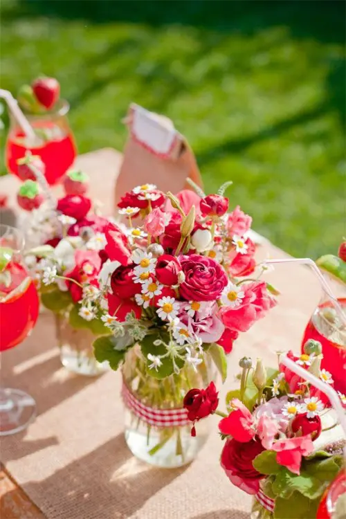 bright pink and white blooms and greeneyr in jars plus a burlap table runner for decorating a table
