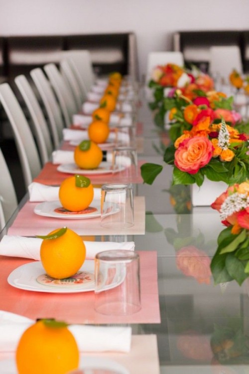 a bright summer bridal shower table with bold blooms and greenery, colorful textiles, citrus with tags