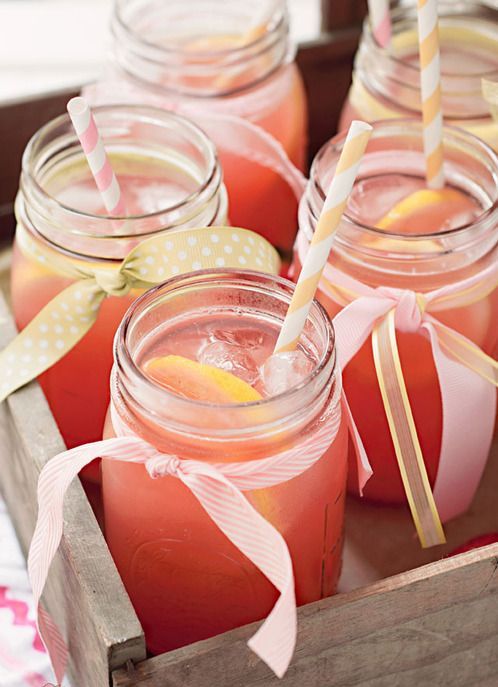 pour pink lemonade into jars, add citrus slices and straws and serve them in wooden boxes to stick to rustic wedding style