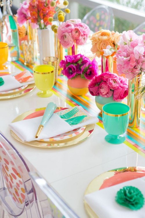 a bright and colorful summer bridal shower tablescape with bold blooms in vases, colorful vases and glasses, colorful plates and napkins