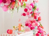a bright summer bridal shower space decorated with colorful blooms, greenery and balloons, with a pink flamingo cake and pink lemonade