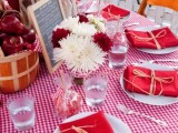 a bright summer bridal shower tablescape with plaid and solid linens, white and red blooms, an apple centerpiece