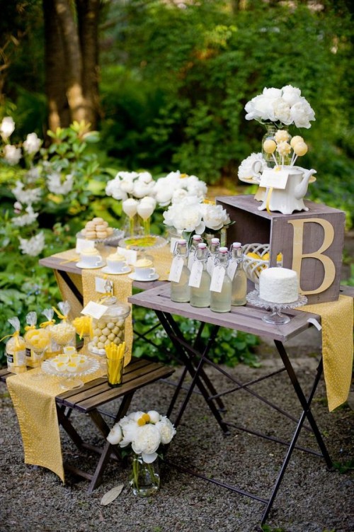 a chic yellow rustic table with lemonade, white blooms, delicious desserts done in yellow and decorated with linens and monograms