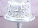 a white wedding cake decorated with edible blooms and lace is a stylish dessert for a modern romantic wedding