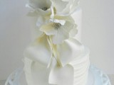 a white textural wedding cake decorated with white sugar bloms and bows is a romantic and refined dessert