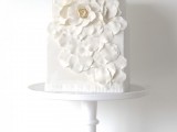 a square wedding cake decorated with a large whiet sugar bloom and petals is a lovely and chic idea