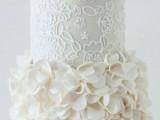 a white patterned wedding cake with a ruffle tier, large sugar blooms is a stylish refined idea for a glam wedding