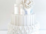 a white wedding cake with a petal, stripe and plain tier, with a silver one, sugar blooms and leaves