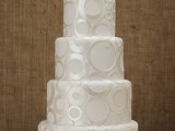 a white wedding cake decorated with shiny metallic circles is a stylish idea for a modern wedding