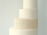 a charming white wedding cake with plain and beaded tiers and a large sugar bloom on top