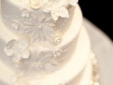 a white patterned wedding cake decorated with beads and sugar blooms is a very romantic vintage-inspired piece