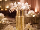 a sophisticated gold and white wedding tablescape with gold vases and white orchids, white linens and gold candleholders and other pretty stuff