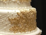 a beautiful wedding cake in white and gold, with edible flowers, pearls, beads, textures and other stuff
