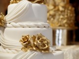 a white draped wedding cake with gold sugar roses is a fantastic idea for a modern glam wedding