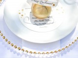 a pretty and refined wedding place setting with a gold edge charger, white plates and a gilded pear plus a card
