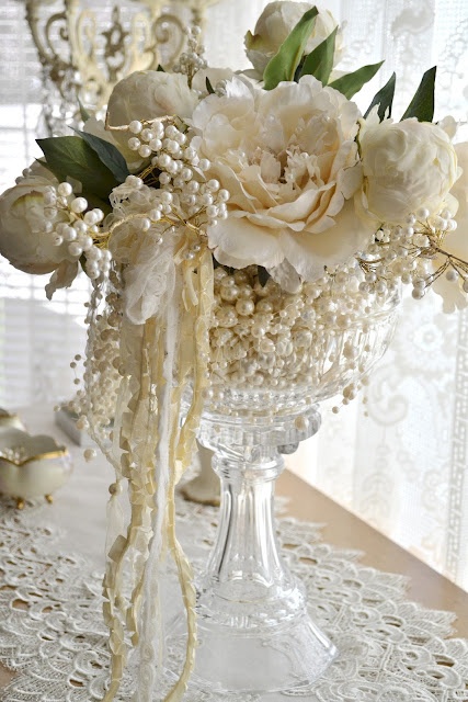 a crystal bowl with pearls, white blooms, leaves and ribbons is a lovely centerpiece for a wedding, with a vintage feel