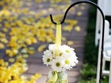 yellow petals on the aisle and white flower arrangements with yellow ribbons to line up the aisle and give it a fresh feel