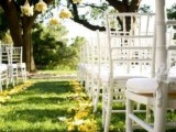 yellow petals on the ground and yellow bloom arrangements hanging over the aisle is a bold and bright idea for a colorful spring wedding