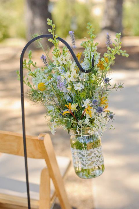 a beautiful and textural wildflower arrangement with yellow, white and blue blooms and greenery is amazing for a wildflower spring or summer wedding aisle