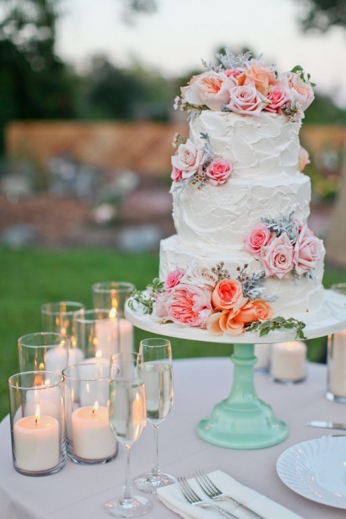 a white textural buttercream wedding cake with pastel and bright blooms and pale greenery is a lovely idea for a spring or summer wedding