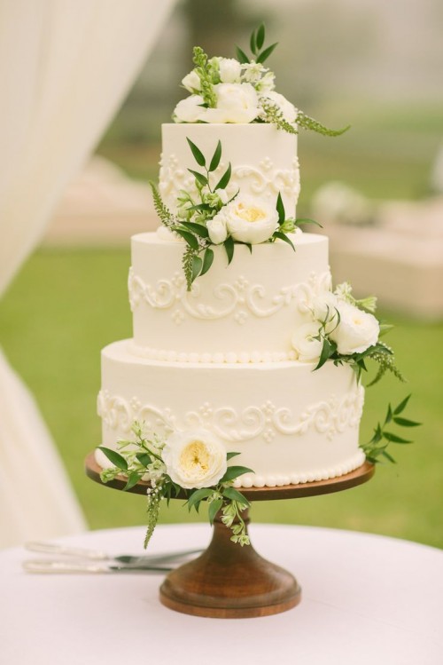 a white textural buttercream wedding cake with patterns, white ranunculus and astilbe is a beautiful vintage-inspired idea for a spring wedding