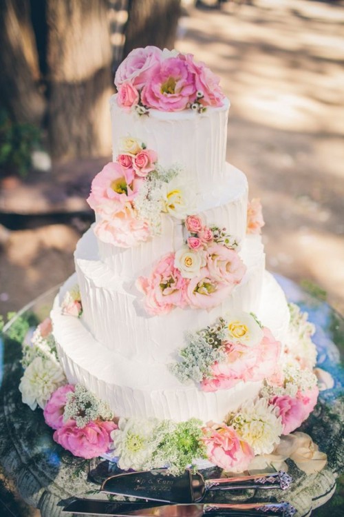 a white textural buttercream wedding cake with white, blush and pink blooms, green flowers is a pretty and delicate spring wedding dessert