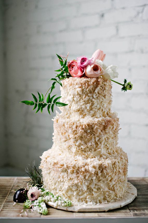 a neutral textural buttercream wedding cake with white, blush and pink blooms and greenery on top for a spring or summer wedding