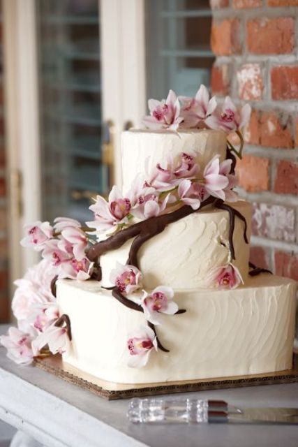 a white textural buttercream wedding cake decorated with a sugar branch and natural pink cherry blossom is a lovely and unusual idea
