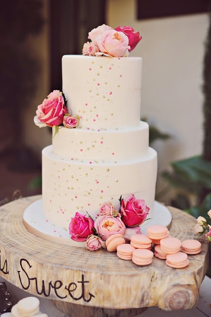 a white buttercream wedding cake with gold and pink polka dots, pink and coral roses and macarons is a bold idea for a bright spring or summer wedding