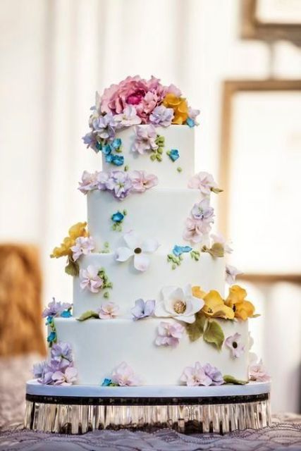 a white buttercream wedding cake decorated with pastel sugar blooms looks cute and chic and will match a spring wedding