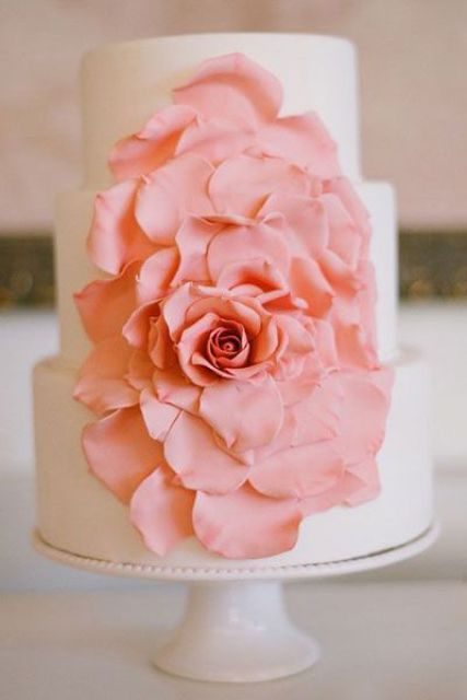a white buttercream wedding cake with an oversized coral bloom is a cool idea for a flower filled wedding in spring or summer