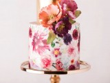 a beautiful wedding cake with a printed floral tier and a gold one, with bright fresh blooms