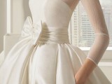 a romantic modern wedding ballgown with an illusion neckline, a large bow, long sleeves and a pleated skirt is wow