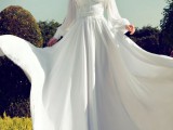 a beautiful and romantic wedding dress of plain fabric, with lace detailing, a pleated skirt and a matching coverup with long sleeves