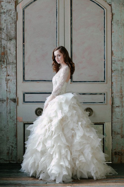 a whimsy wedding ballgown with a lace bodice with long sleeves, a cutout back and a layered feathered skirt looks very cool