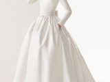 a plain wedding ballgown with a bodice with long sleeves, a high neckline and a pleated skirt with pockets looks non-typical and chic