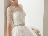 a romantic vintage-inspired wedding ballgown of lace, with a high neckline and short sleeves, an embellished sash and lace gloves to finish off the look
