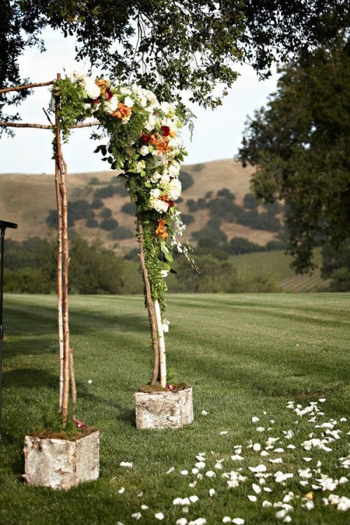 a fall vineyard wedding arch of branches, rust and white blooms and greenery is a lovely idea for a fall vineyard wedding