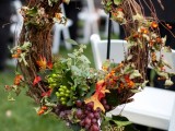 a fall vineyard wedding wreath of bright leaves, greenery, berries, grapes is a pretty decoration for any part of your venue