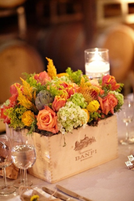 a bright fall vineyard wedding tablescape with bold blooms and greenery in a crate, candles and neutral linens is a very cool and fresh idea