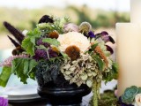 a lovely fall vineyard wedding tablescape with patterned plates and chargers, white and dark blooms and greenery, candles and succulents is amazing for a vineyard wedding