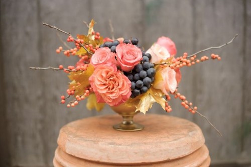 a chic fall vineyard wedding centerpiece of pink blooms, grapes, berries on branches is a lovely idea that you can DIY