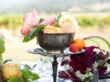 a simple and chic fall vineyard wedding centerpiece of pink and dark blooms, apples and berries and greenery is a very cool idea