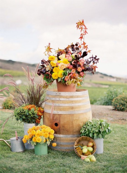 bright fall vineyard wedding decor of bold and dark blooms, dark foliage, greenery, apples and floral arrangements is a very cool idea