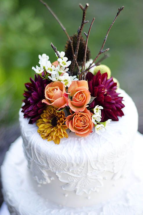 a white lace wedding cake topped with bright fall blooms is an elegant and chic idea for a fall wedding, whether it's a vineyard one or not