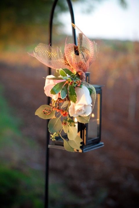 a fall wedding aisle decoration with a candle lantern, greenery, white blooms and rust fabric is a lovely idea