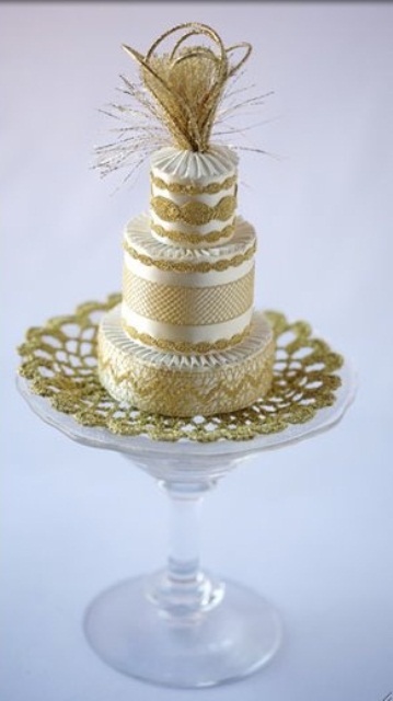 an exquisite gold and white patterned wedding cake with lace and some fringe on top is a stylish option