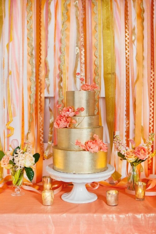 a shiny glam gold wedding cake with coral sugar blooms is a nice idea for a modern bright wedding