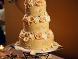 a beautiful gold wedding cake with various patterns and peachy and white blooms is a chic and cool idea