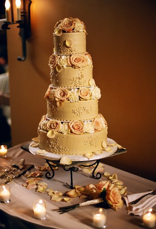 A beautiful gold wedding cake with various patterns and peachy and white blooms is a chic and cool idea